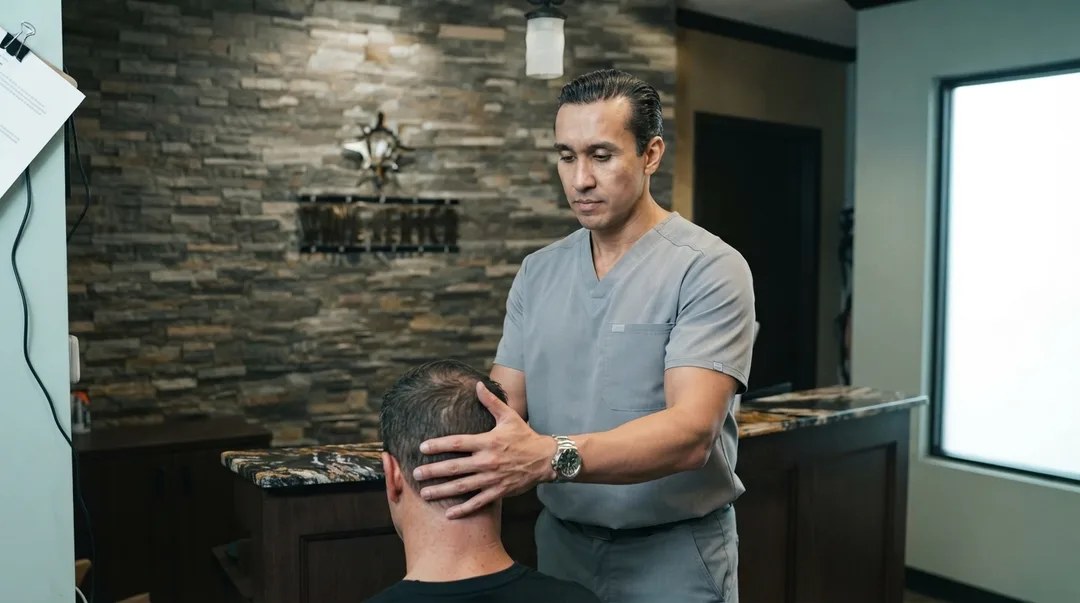 NUCCA Doctor using a gentle hand position at a patient’s upper neck during a measured upper-spinal assessment